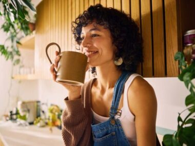 Femme souriante buvant son thé assise dans sa cuisine minimaliste