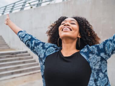 Jeune femme ouvrant les bras et ayant un visage heureux et souriant