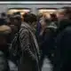 Femme souffrant de stress chronique marchant seule devant un métro bondé de monde